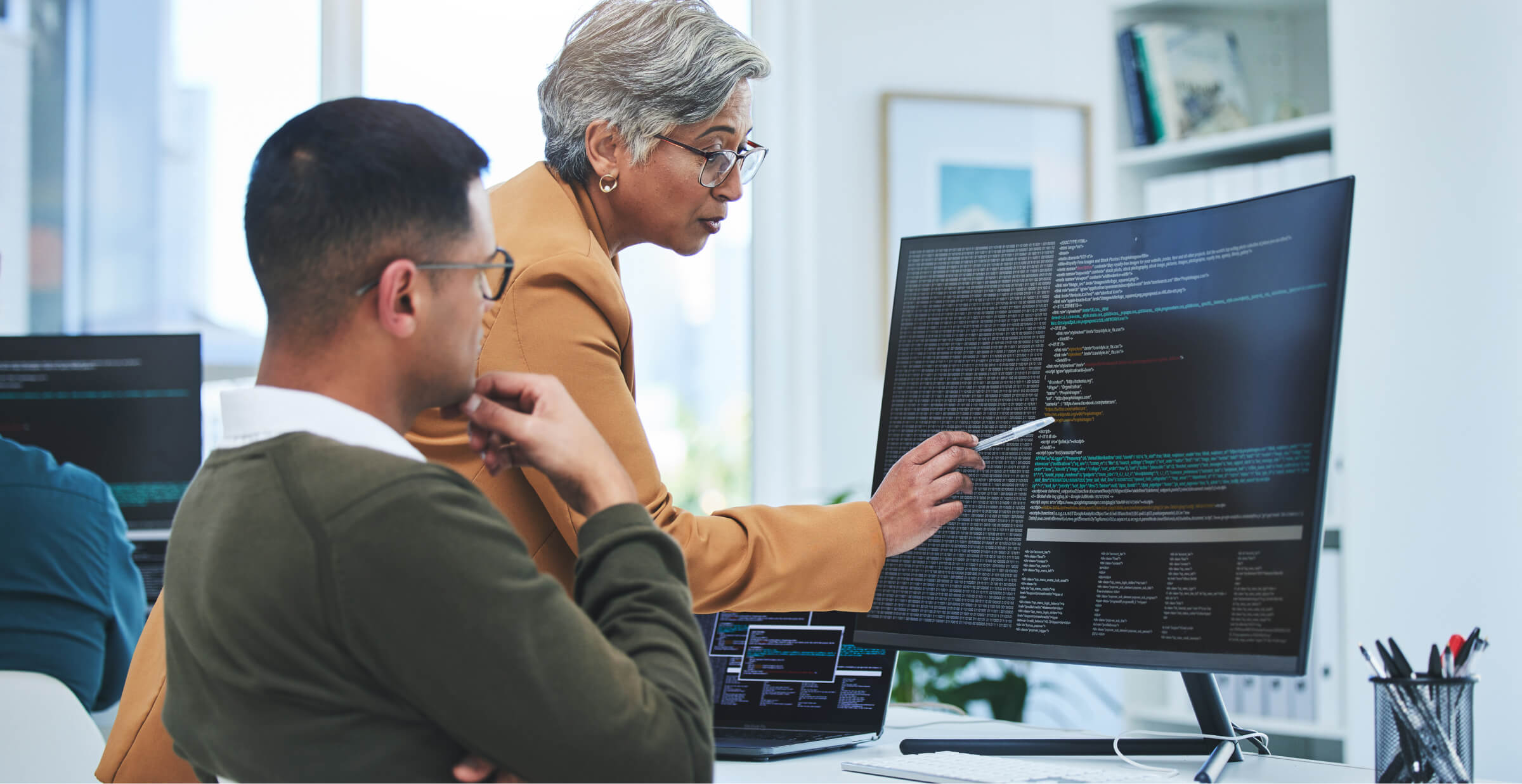 Senior software engineer mentoring a junior colleague on coding practices, highlighting collaboration in tech industry