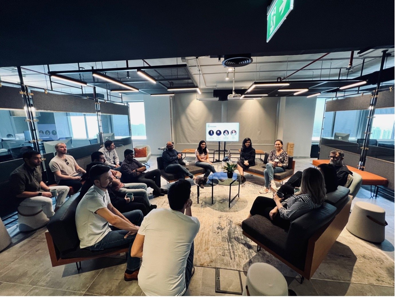 Multiple people, men and women, sitting around a conference room having a discussion.