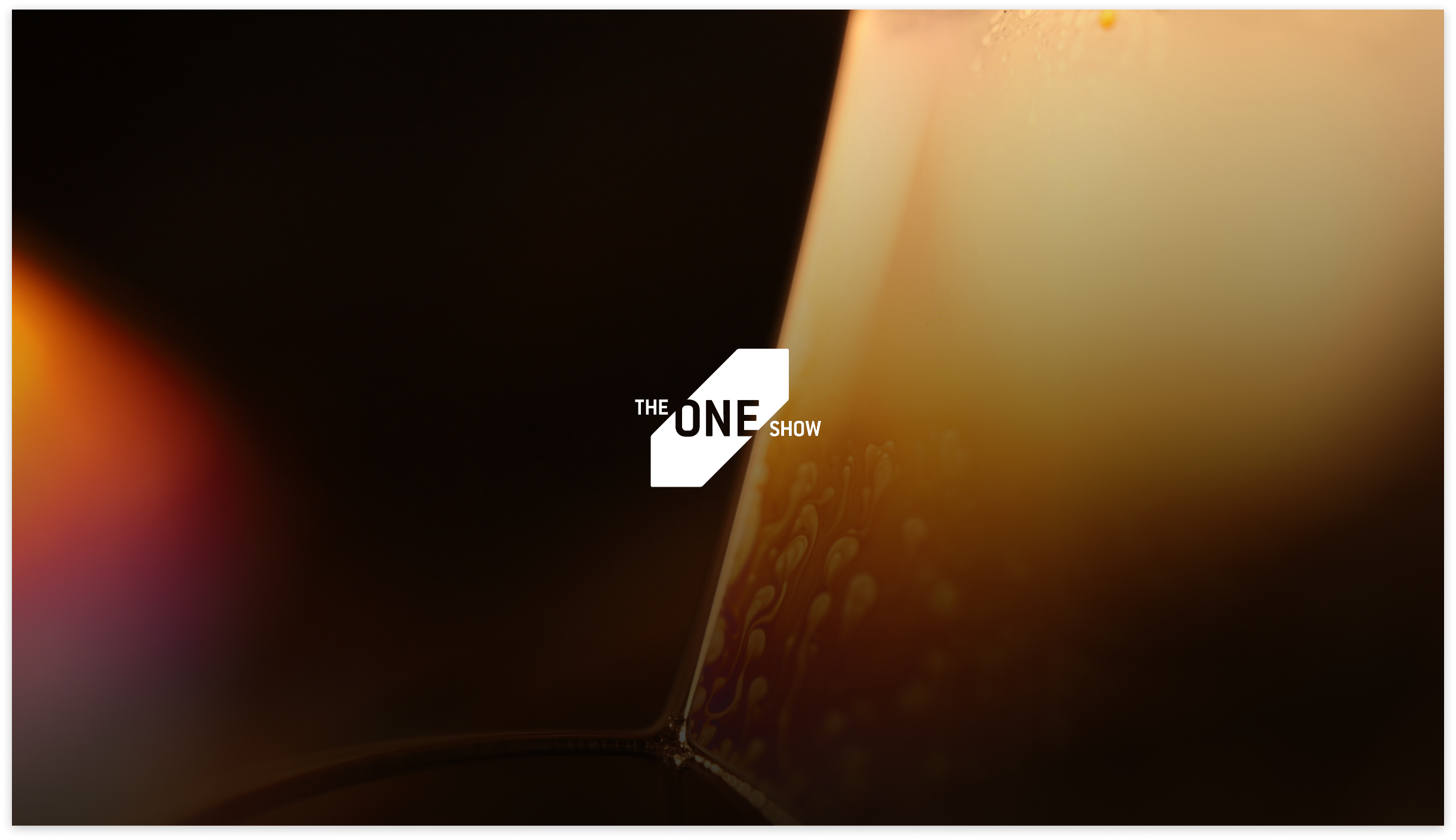 The One Show logo centered on a dramatic dark background with warm lighting, representing recognition in global creative and advertising industry awards.