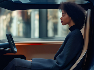 A woman seated in the driver's seat of a car, focused on the road ahead.